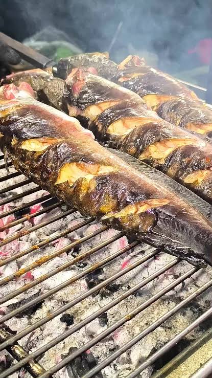 Whole smoked hito grilling over hot coals